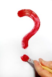 a hand holding a paintbrush and a red question mark